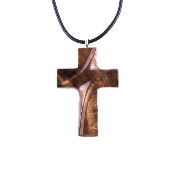 A wooden cross pendant necklace carved in brown wood with black cord. The pendant is intricately detailed and shows the wood grain. This handcrafted necklace is a unique and stylish accessory.